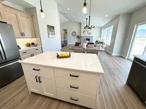 Kitchen with light hardwood / wood-style flooring, lofted ceiling, and stainless steel fridge