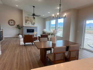 Dining area featuring ceiling fan with notable chandelier, lofted ceiling, and wood-type flooring