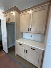 Kitchen featuring light brown cabinets, dark wood-type flooring, light stone counters, and a textured ceiling