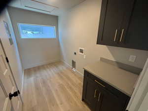 Clothes washing area featuring cabinets, hookup for a washing machine, light wood-type flooring, and electric dryer hookup