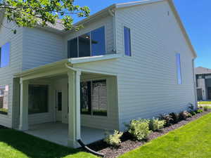 Rear view of house with a patio area and a lawn