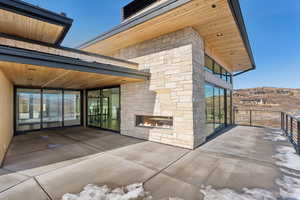 View of patio featuring a balcony and an outdoor stone fireplace