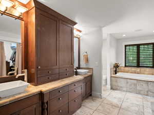 Master bathroom featuring tile flooring, dual vanity, tiled tub, and toilet