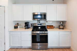 Kitchen featuring stainless steel appliances, white cabinetry, and light hardwood / wood-style flooring