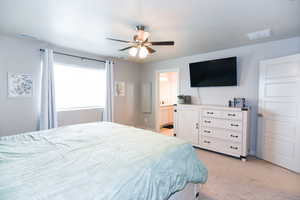 Bedroom featuring ensuite bath, ceiling fan, and light carpet