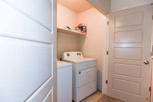 Clothes washing area with light colored carpet and washer and clothes dryer