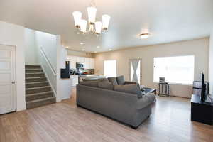 Living room with plenty of natural light, sink, light wood-type flooring, and a notable chandelier