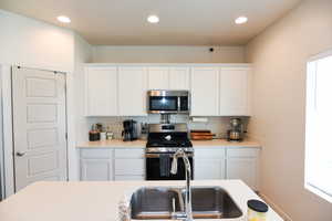 Kitchen featuring white cabinetry, sink, and stainless steel appliances