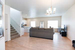 Living room with sink, light hardwood / wood-style flooring, and an inviting chandelier