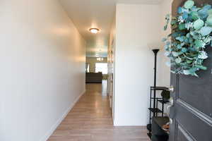 Hallway with light wood-type flooring and an inviting chandelier