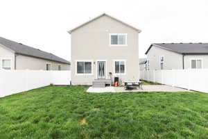 Rear view of house with a yard and a patio