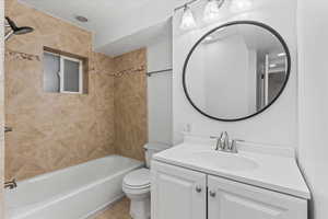 Full bathroom featuring tile flooring, oversized vanity, toilet, and tiled shower / bath combo