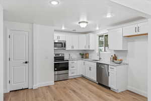 Kitchen featuring light hardwood / wood-style floors, white cabinets, and stainless steel appliances