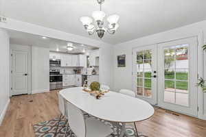 Dining space with sink, light hardwood / wood-style floors, and an inviting chandelier