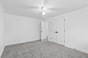 Unfurnished bedroom with a closet, ceiling fan, and carpet floors