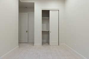 Unfurnished bedroom featuring a closet and light colored carpet