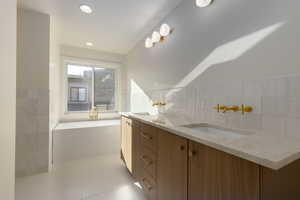 Bathroom with tile floors, dual bowl vanity, and tile walls