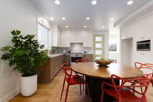 Kitchen featuring light wood-type flooring, stainless steel appliances, white cabinets, backsplash, and sink