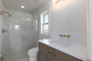 Bathroom featuring an enclosed shower, vanity, and toilet