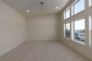 Carpeted empty room featuring ceiling fan