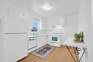 Kitchen featuring sink, light hardwood floors throughout, and white cabinetry