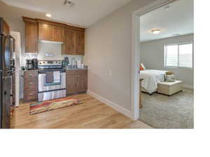 Kitchen featuring light colored carpet, appliances with stainless steel finishes, sink, and light stone countertops