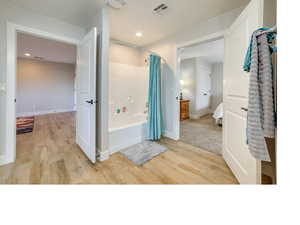 Bathroom with hardwood / wood-style floors and shower / bath combination with curtain