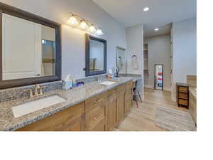 Bathroom with dual vanity and hardwood / wood-style flooring