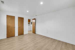 Unfurnished bedroom featuring multiple closets, light wood-type flooring, and washer / clothes dryer