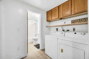 Laundry room with light hardwood / wood-style floors, cabinets, hookup for an electric dryer, hookup for a washing machine, and independent washer and dryer