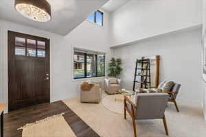 Entrance foyer featuring a healthy amount of sunlight, dark wood-type flooring, a high ceiling, and a chandelier