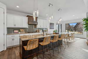 Kitchen with white cabinets, an island with sink, and hanging light fixtures