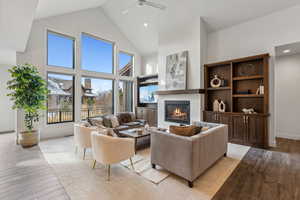 Living room featuring ceiling fan, high vaulted ceiling, and light wood-type flooring