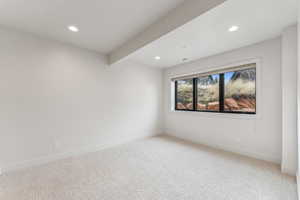 Carpeted spare room featuring beamed ceiling