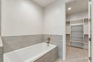 Bathroom with tiled tub and tile patterned flooring