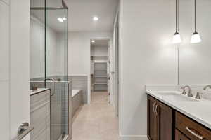 Bathroom featuring tile patterned floors, vanity, and plus walk in shower