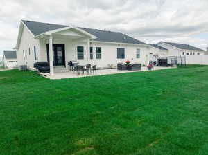 Back of property with a patio, central air condition unit, and a lawn