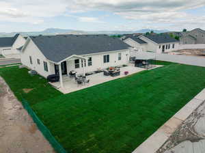 Back of property with a patio, a mountain view, and a lawn