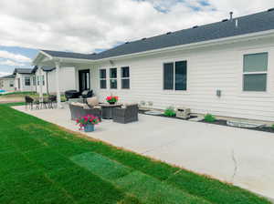 Rear view of house featuring outdoor lounge area, a lawn, and a patio area