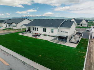 Rear view of house with a patio area, a mountain view, and a yard