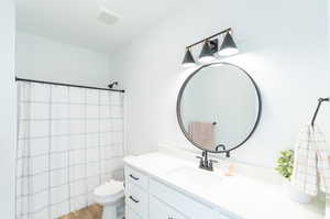 Bathroom with large vanity, toilet, and hardwood / wood-style floors