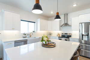 Kitchen with stainless steel appliances, wall chimney exhaust hood, tasteful backsplash, and a kitchen island