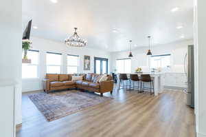 Living room with a healthy amount of sunlight, a notable chandelier, and LVP flooring