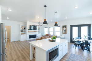 Kitchen featuring a healthy amount of sunlight, light LVP floors, white cabinetry, and appliances with stainless steel finishes