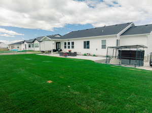 Rear view of house with a yard and a patio area