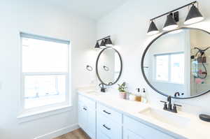 Bathroom featuring vanity with extensive cabinet space, LVP floors, and double sink