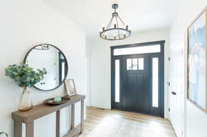 Foyer entrance with a notable chandelier and light LVP flooring