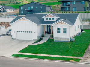 View of front facade with a front yard, a garage, and central air condition unit