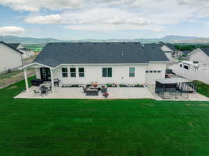 Rear view of property featuring a patio, an outdoor living space, and a yard