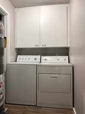 Washroom with dark hardwood / wood-style floors, washer and dryer, a textured ceiling, water heater, and cabinets